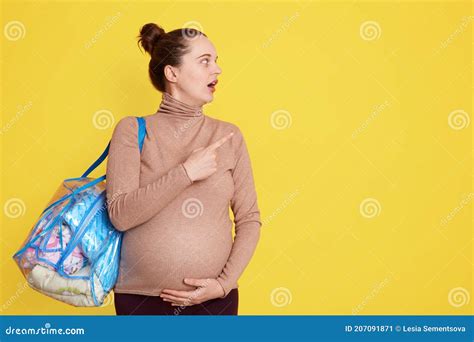 Young Pregnant Woman In Casual Attire With Belly Pointing Aside With