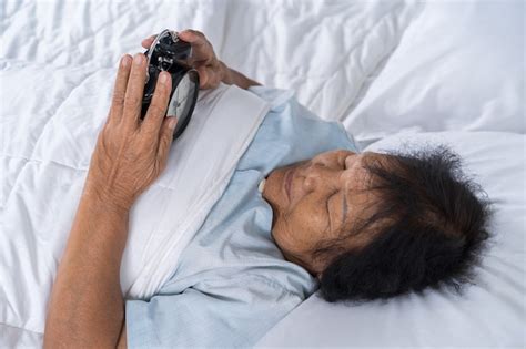 Premium Photo Senior Woman In Bed Pressing Snooze Button On Morning