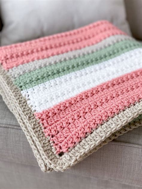 A Crocheted Blanket Sitting On Top Of A Couch Next To A White Pillow