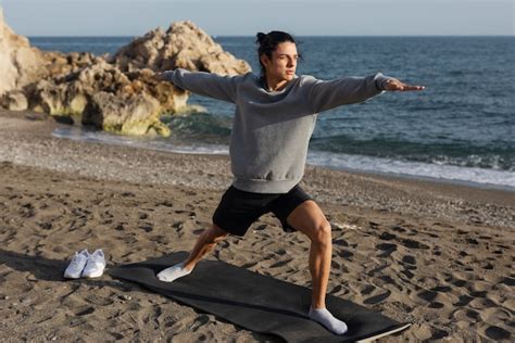 Hombre De Tiro Completo Haciendo Yoga En La Playa Foto Gratis