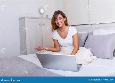 Portrait Of A Young Smiling Woman Sitting With Laptop On Bed Happy