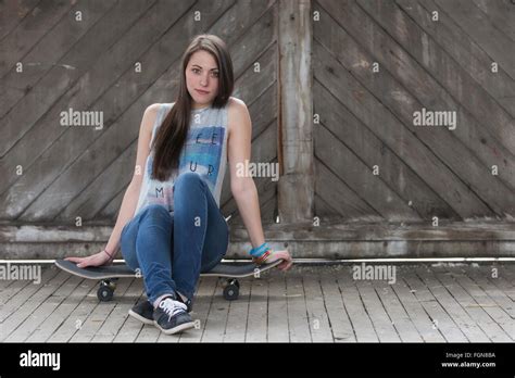 Beautiful Brunette Woman Sitting On A Skateboard In A Warehouse Stock Photo Alamy