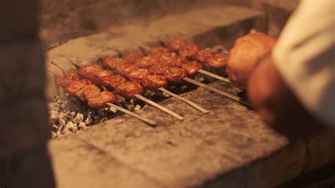 A Man S Hand Flips Skewers With Barbecue Roasting On The Grill