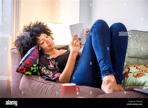 Mature Woman Reclining On Sofa Reading Book Stock Photo Alamy