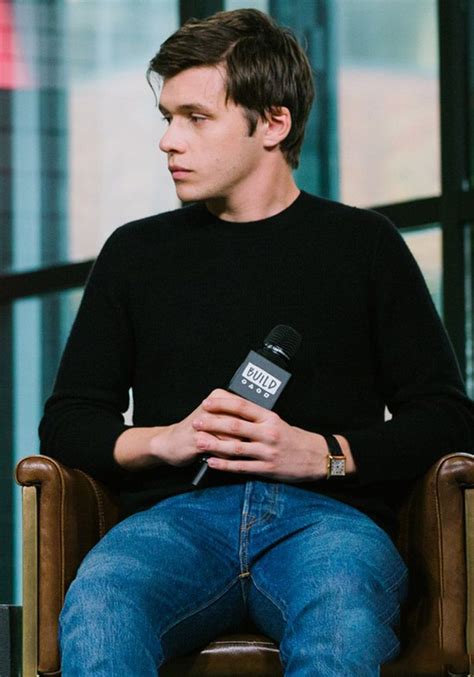 a man sitting in a chair holding a microphone and looking off into the ...