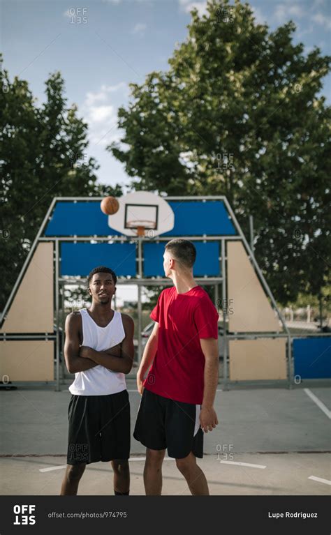 Young multiracial teenagers on a basketball court will ball in the air behind them stock photo ...