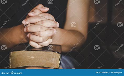 Hands Folded In Prayer On A Holy Bible In Church Concept For Faith