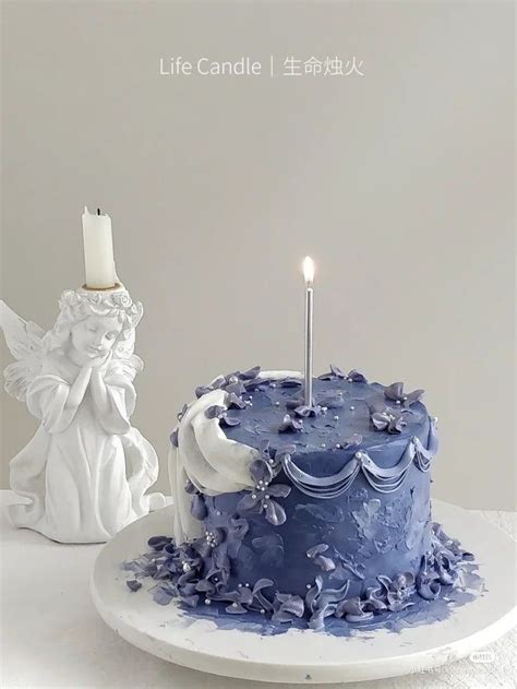 A Blue Cake Sitting On Top Of A White Plate Next To A Small Candle Holder