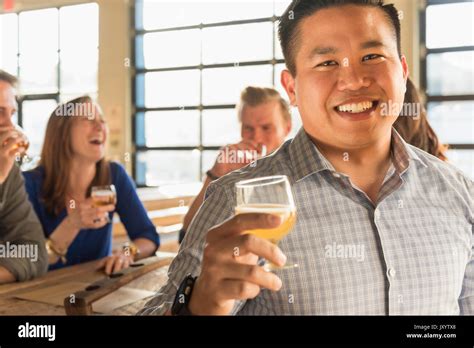 Portrait Of Smiling Man Drinking Beer With Friends In Brew Pub Stock