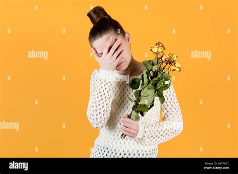 Girl Covers Her Face In Crying She Holds Withered Flowers In Her Hands