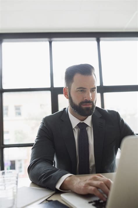 Brunette Businessman With Beard Using Laptop In Office By Hero Images Handsome Bearded Men