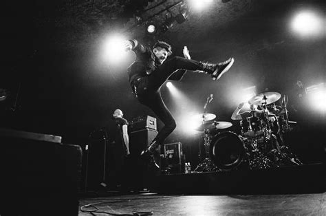 Black And White Photograph Of A Man On Stage With His Legs Up In The Air