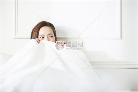 躲在被窝里微笑的年轻女子高清图片下载 正版图片502194328 摄图网