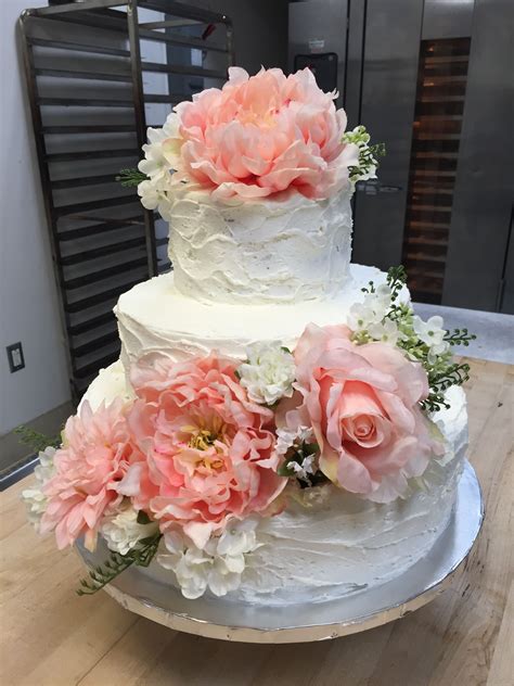 A Three Tiered White Cake With Pink Flowers On The Top And Bottom