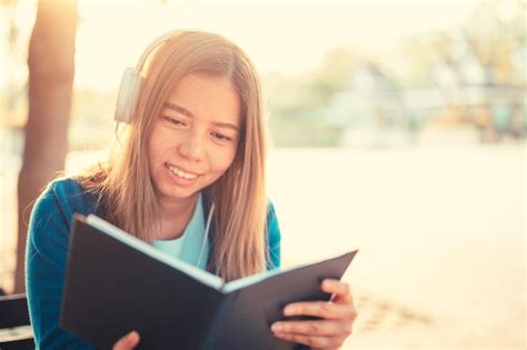 Mujer joven sonriente leyendo un libro mientras está sentada en un