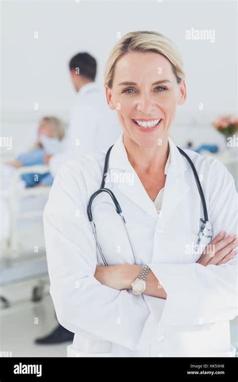 Smiling Doctor With Arms Crossed In Front Of A Patient And A Doctor