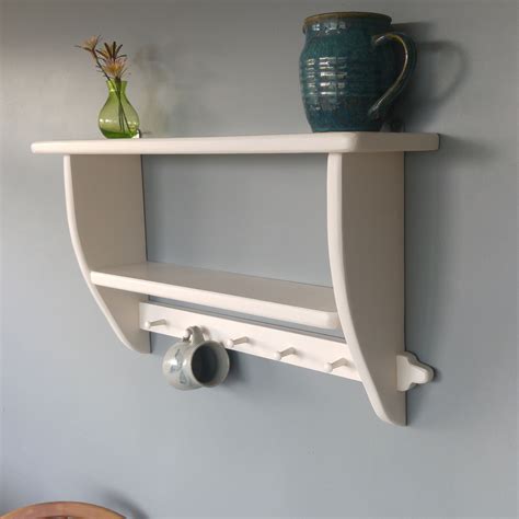 A White Shelf With Two Hooks On It And A Vase Sitting On Top Of It