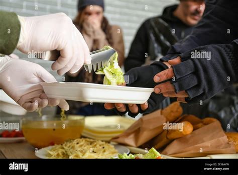 Volunteer giving food to homeless people in warming center Stock Photo ...