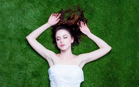 Portrait Of A Young Redhead Woman Lying Down On Green Spring Grass