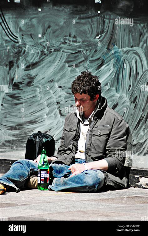 Young Homeless Man Drinking Cider Sitting On The Street Stock Photo Alamy