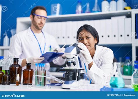 Man And Woman Scientists Using Microscope Working At Laboratory Stock