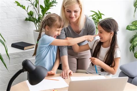 Belle jeune mère aidant ses filles à faire leurs devoirs Photo Premium