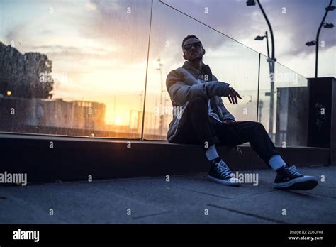 Low Angle Shot Of A Young Cool Male Sitting And Posing During Sunset
