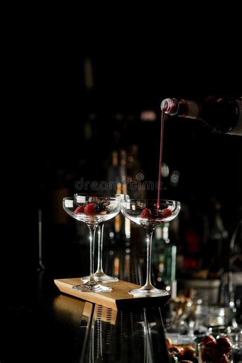 Barman S Hand Holds Bottle With Red Syrup And Pours It Into Three