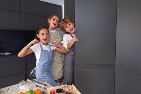 Niños felices parados en la cocina mientras cocinan juntos Foto Premium