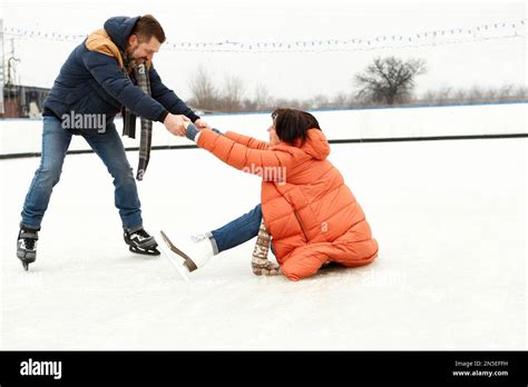 Middle Aged Positive Couple Skating On Open Air Ice Rink Man Helping