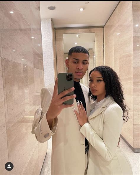 A Man And Woman Taking A Selfie In Front Of A Wall With Marble Walls