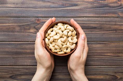 Premium Photo Woman Hands Holding A Wooden Bowl With Cashew Nuts