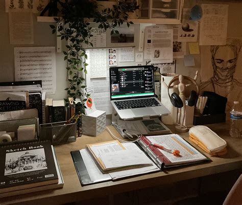 An Office Desk With A Laptop Books And Papers On It In Front Of A Plant