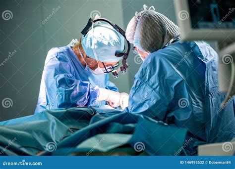 Surgeon and His Assistant Performing Cosmetic Surgery in Hospital Operating Room. Surgeon in ...