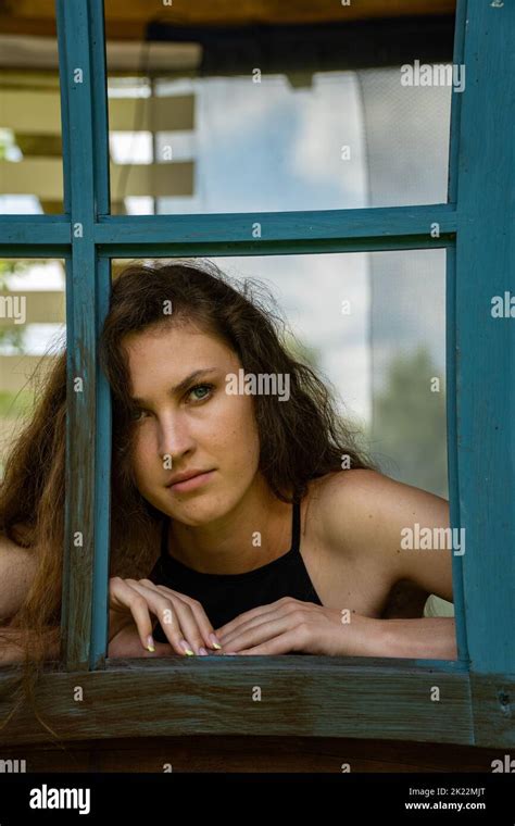 Shot Of Sad Young Woman Crying While Looking Through The Window At Home