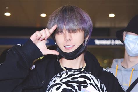 A Man With Purple Hair Wearing A Mask And Holding His Hand Up To His Face