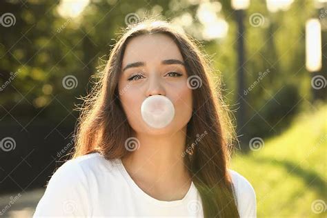 Beautiful Young Woman Blowing Bubble Gum In Park Stock Photo Image Of