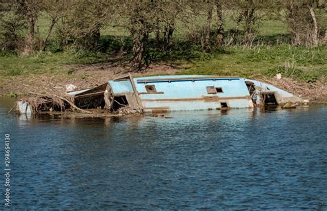 Wreck of a wooden barge seen decaying at the side of an inland waterway ...