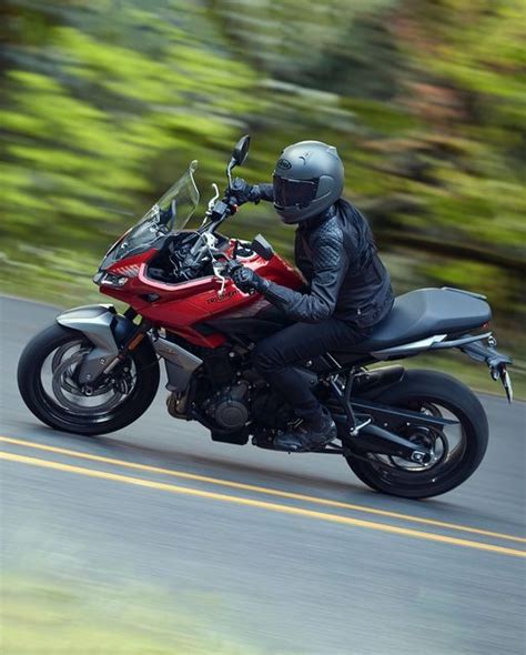 A Man Riding On The Back Of A Red Motorcycle