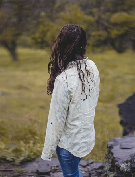 Woman In White Long Sleeve Shirt And Blue Denim Jeans Standing On Green Grass Field During Photo