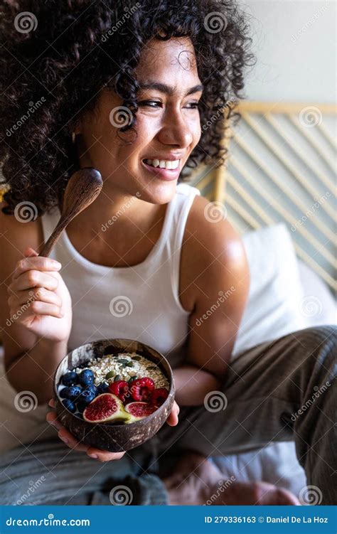 Retrato Vertical De Una Joven Latina Feliz Sonriendo Comiendo Cuenco De Desayuno Saludable De