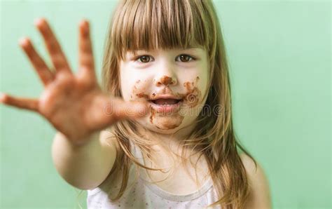 Uma Doce E Fofa Menina Chocolate Coberto Pelo Rosto E Pelos Dedos