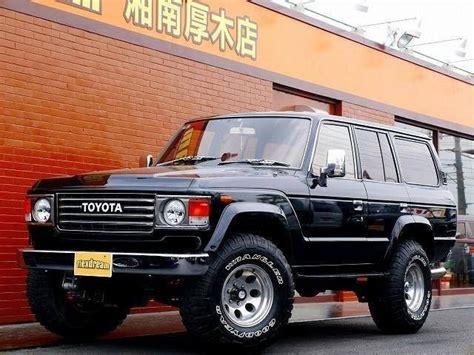 A Black Suv Parked In Front Of A Brick Building With Chinese Writing On