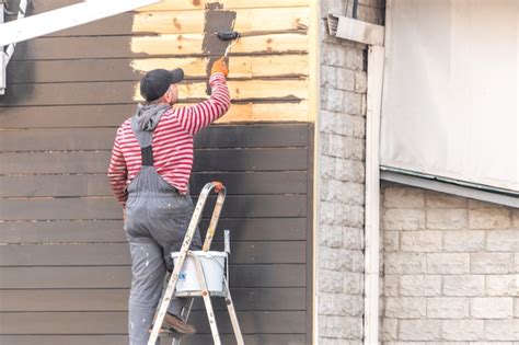 Um Homem Pintando Uma Parede De Madeira Do Lado De Fora Foto Premium