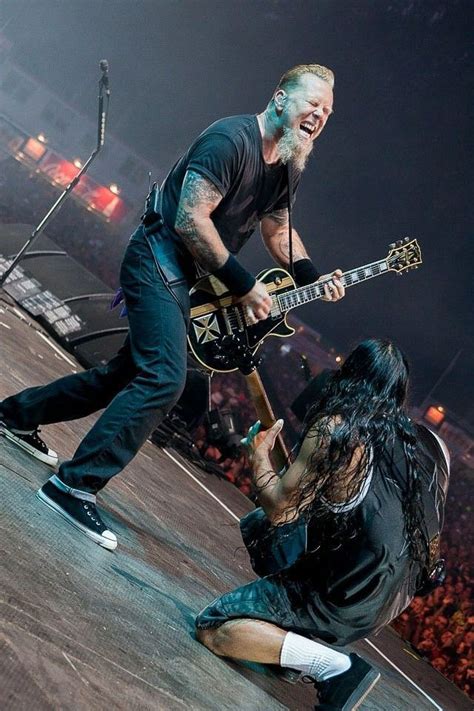 an image of a man playing guitar on stage with people watching from the ...