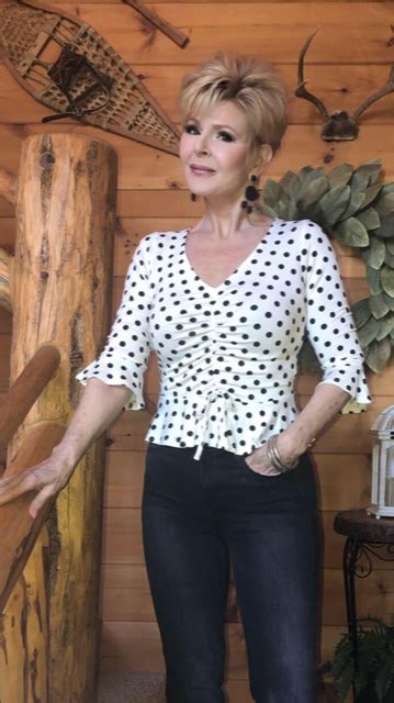 A Woman Standing In Front Of A Wooden Wall Wearing Jeans And A Polka