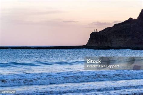 Siluet Dua Orang Berdiri Di Atas Batu Di Pantai Di Kejauhan Konsep