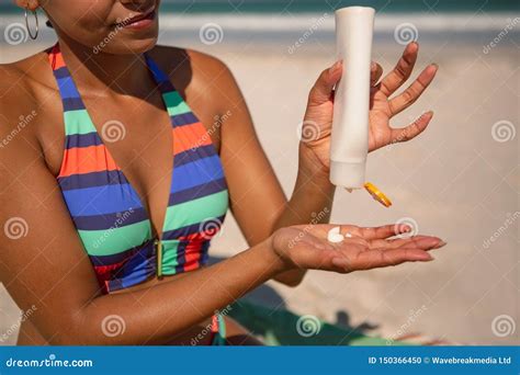 Woman In Bikini Applying Sunscreen Lotion At Beach In The Sunshine