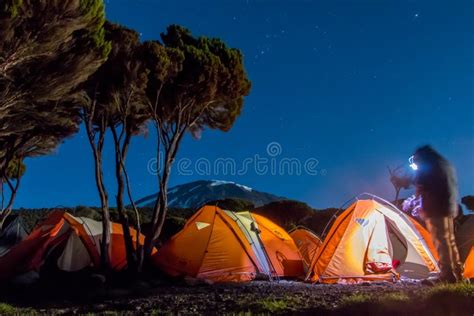 Orange Tents Illuminated Before Mount Kilimanjaro During Night Stock