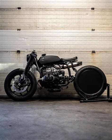 A Black Motorcycle Parked In Front Of A Garage Door Next To A White Brick Wall